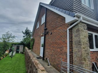White uPVC bargeboard and roofline trim on a gable end with new black downpipe