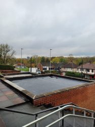 Large commercial flat roof replacement with EPDM rubber membrane inside parapet walls