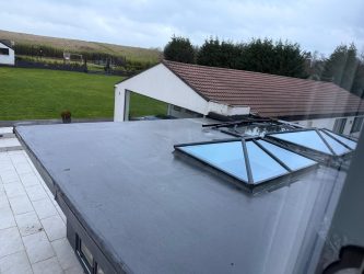 Large flat rubber roof with twin roof lanterns flooding the extension below with light