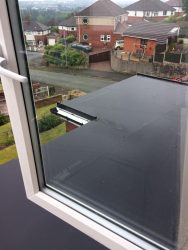 Newly installed EPDM flat roof with black aluminium guttering viewed from above