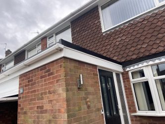 Front porch canopy flat roof finished with white uPVC fascias and black edge trim