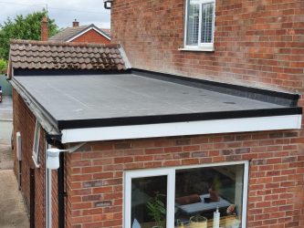Rear extension EPDM rubber flat roof with black edge trims beside a tiled pitched roof